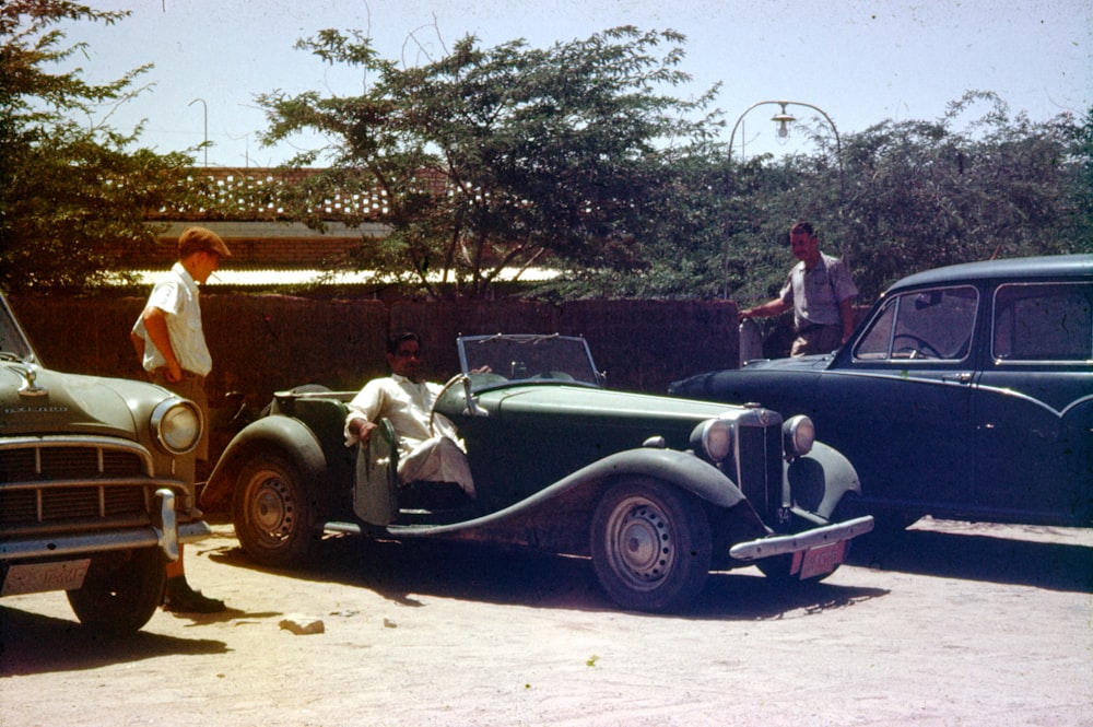 man in black jacket standing beside black and white car during daytime