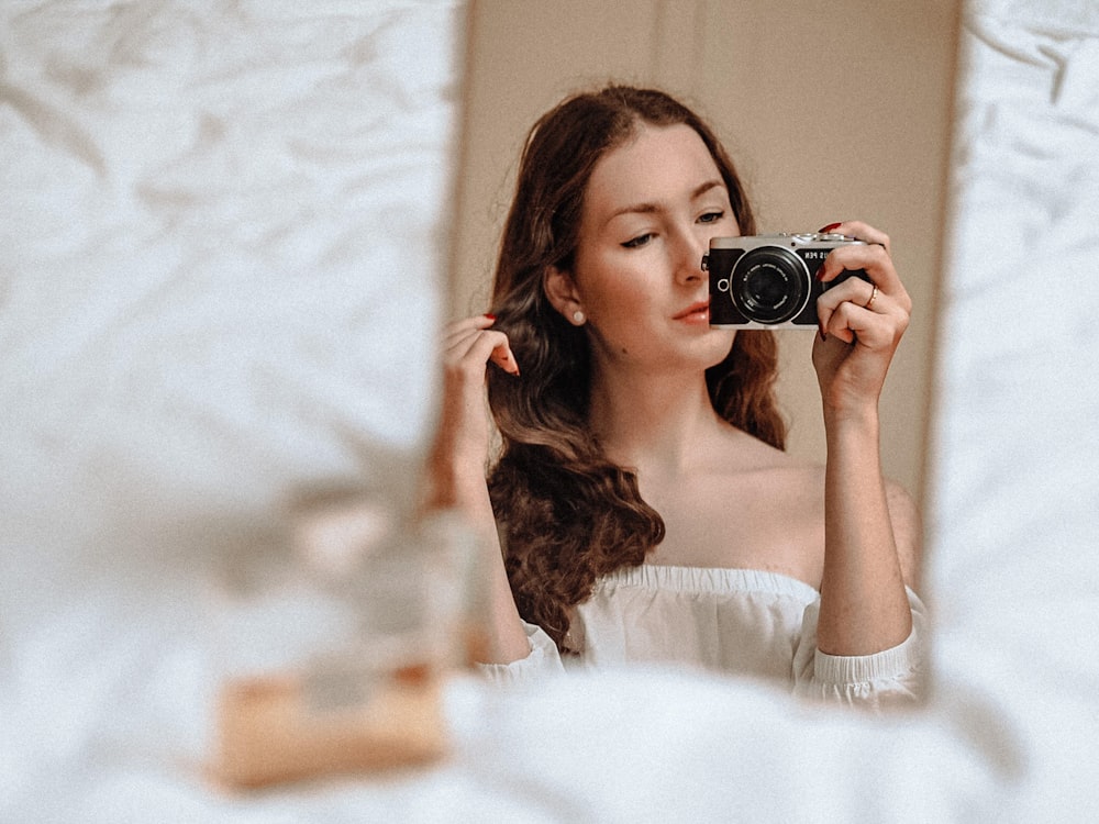 woman in white long sleeve shirt holding black camera