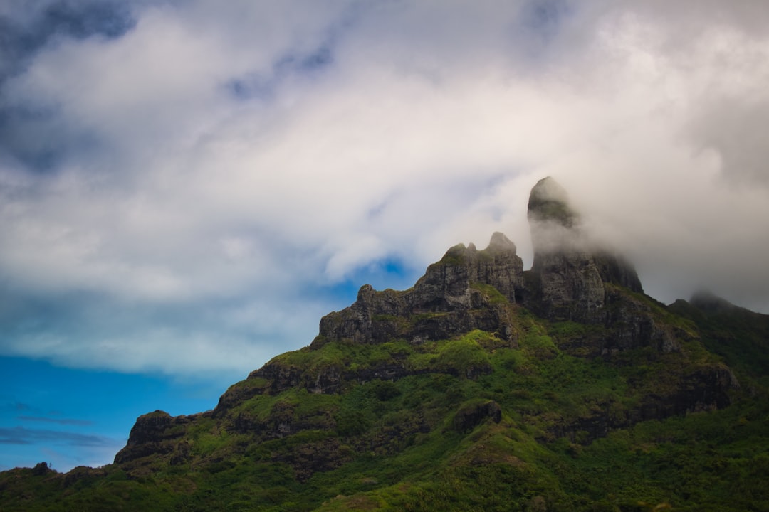 a very tall mountain with some clouds in the sky,