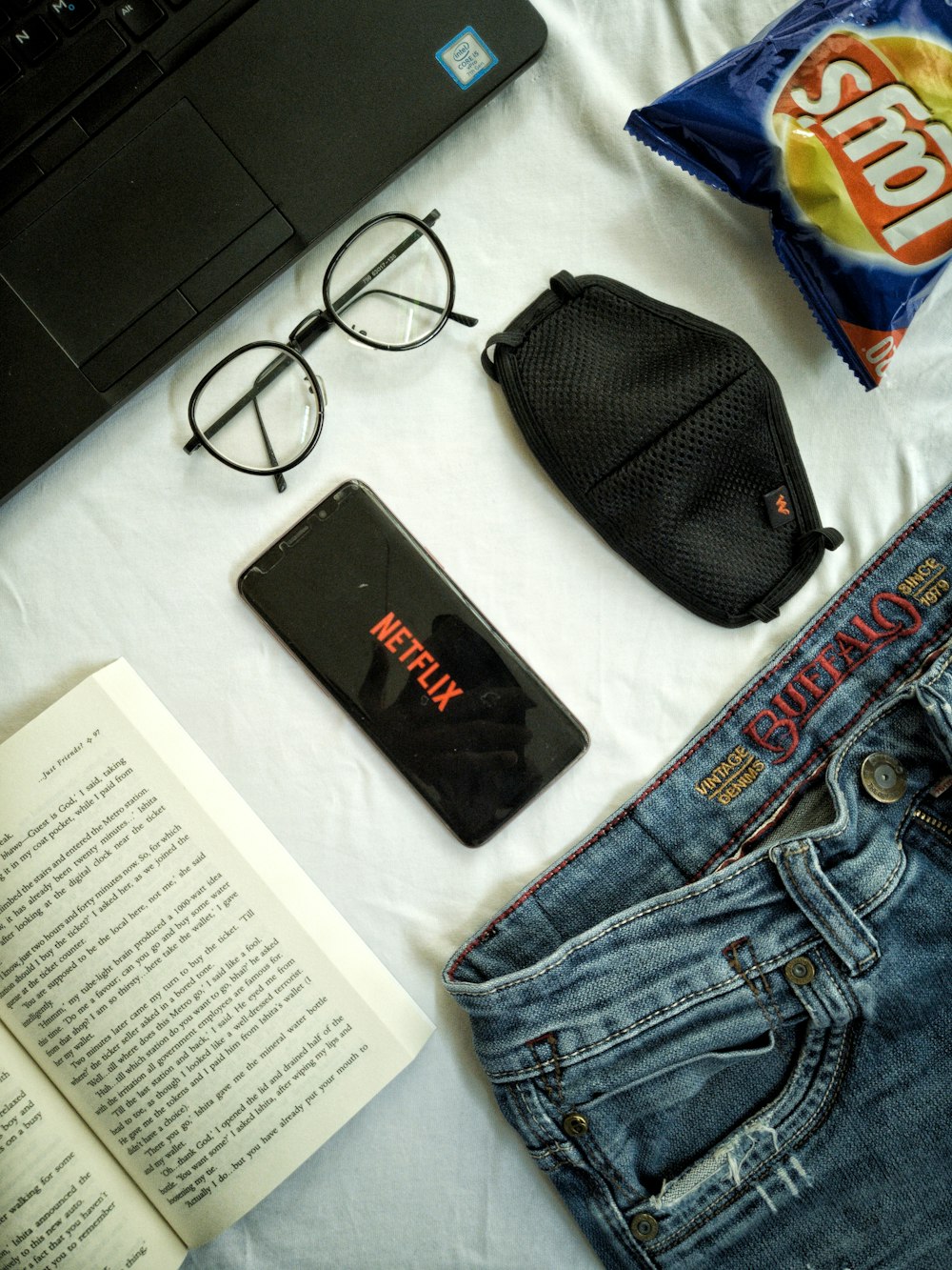 black framed eyeglasses beside black leather pouch and blue denim jeans