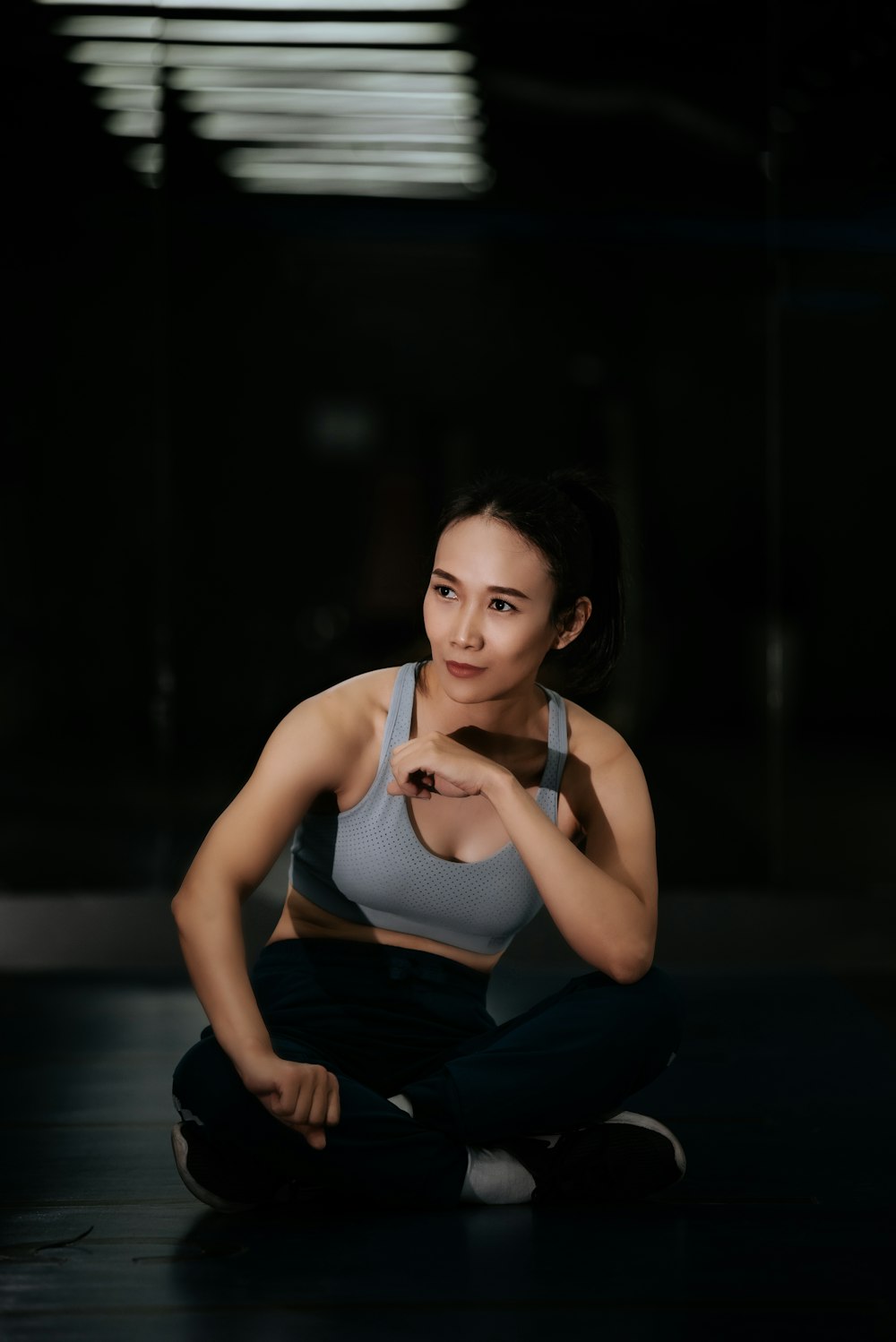 woman in white tank top and black pants sitting on floor