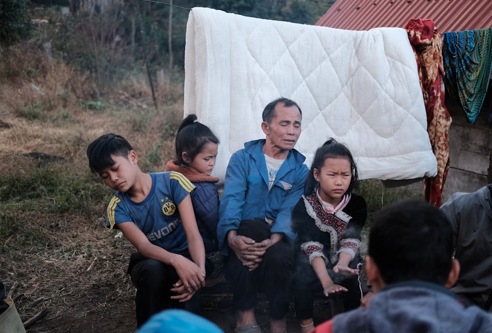 3 boys and 2 girls sitting on ground during daytime