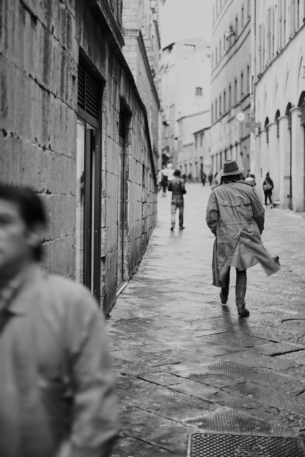 grayscale photo of man walking on sidewalk