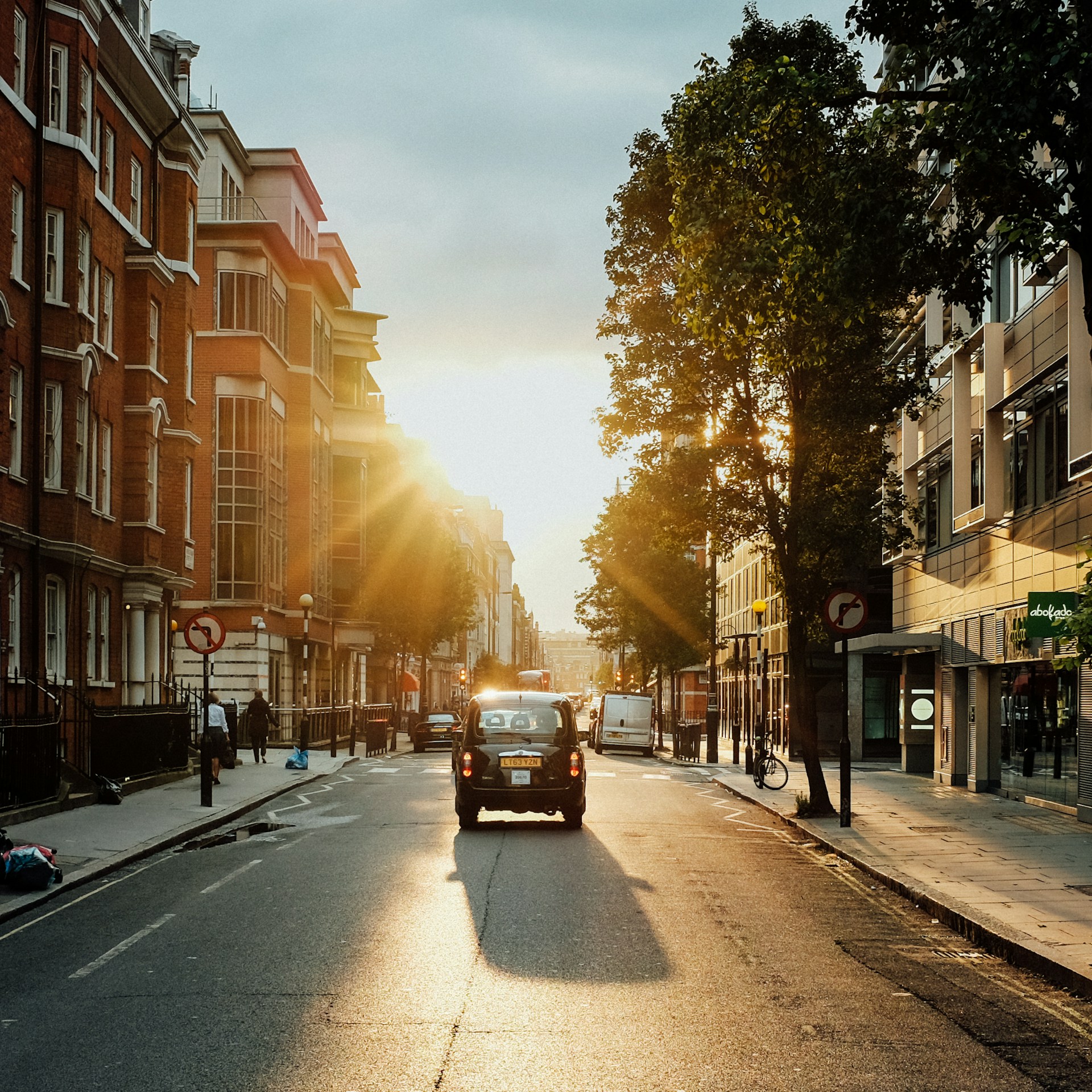 cars on road between buildings during sunset