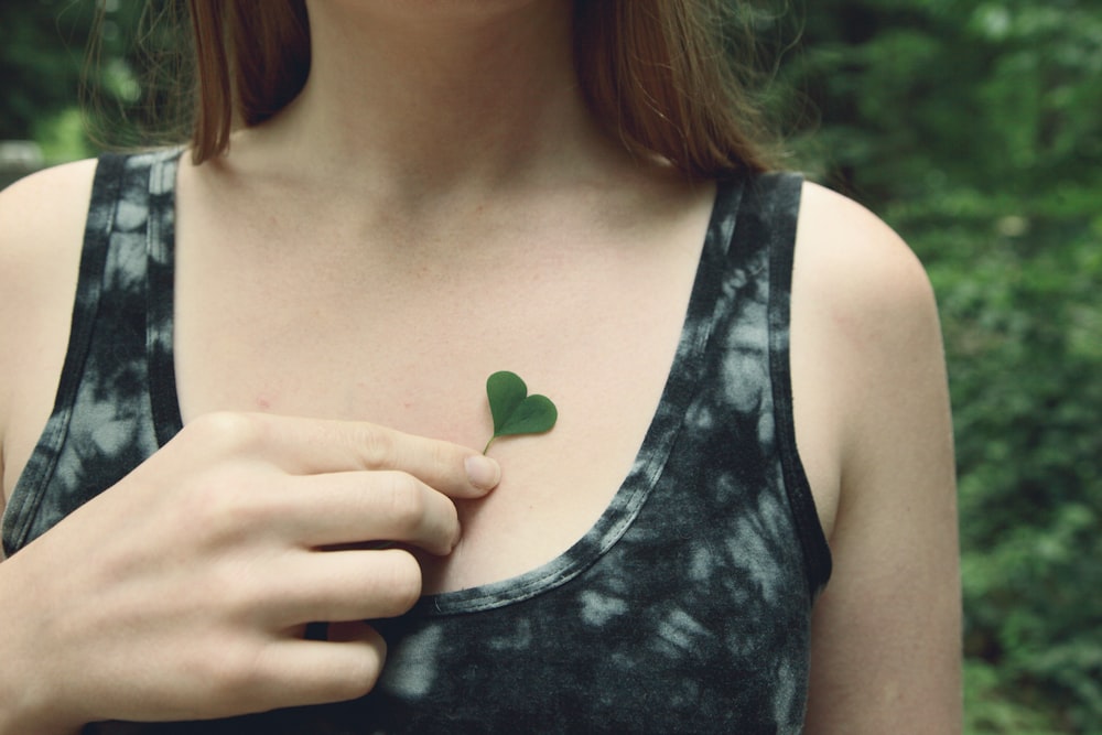 woman in black tank top holding green leaf