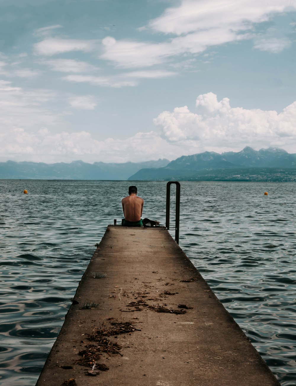 woman in black tank top sitting on brown wooden dock during daytime