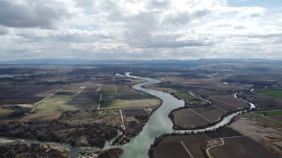 Wide shot of a river cutting through farmland in morning light.