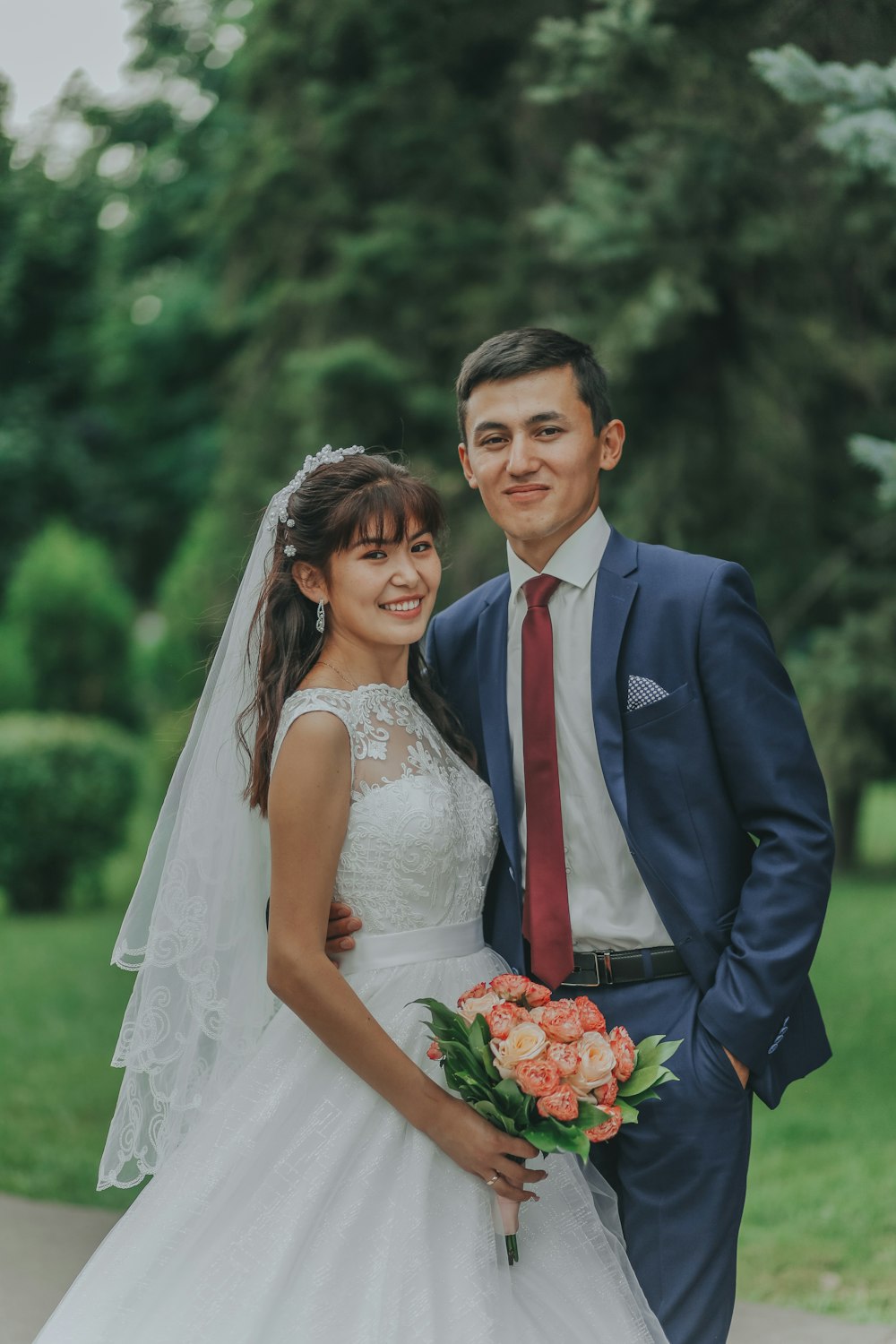 man in blue suit jacket and woman in white wedding dress holding bouquet of flowers