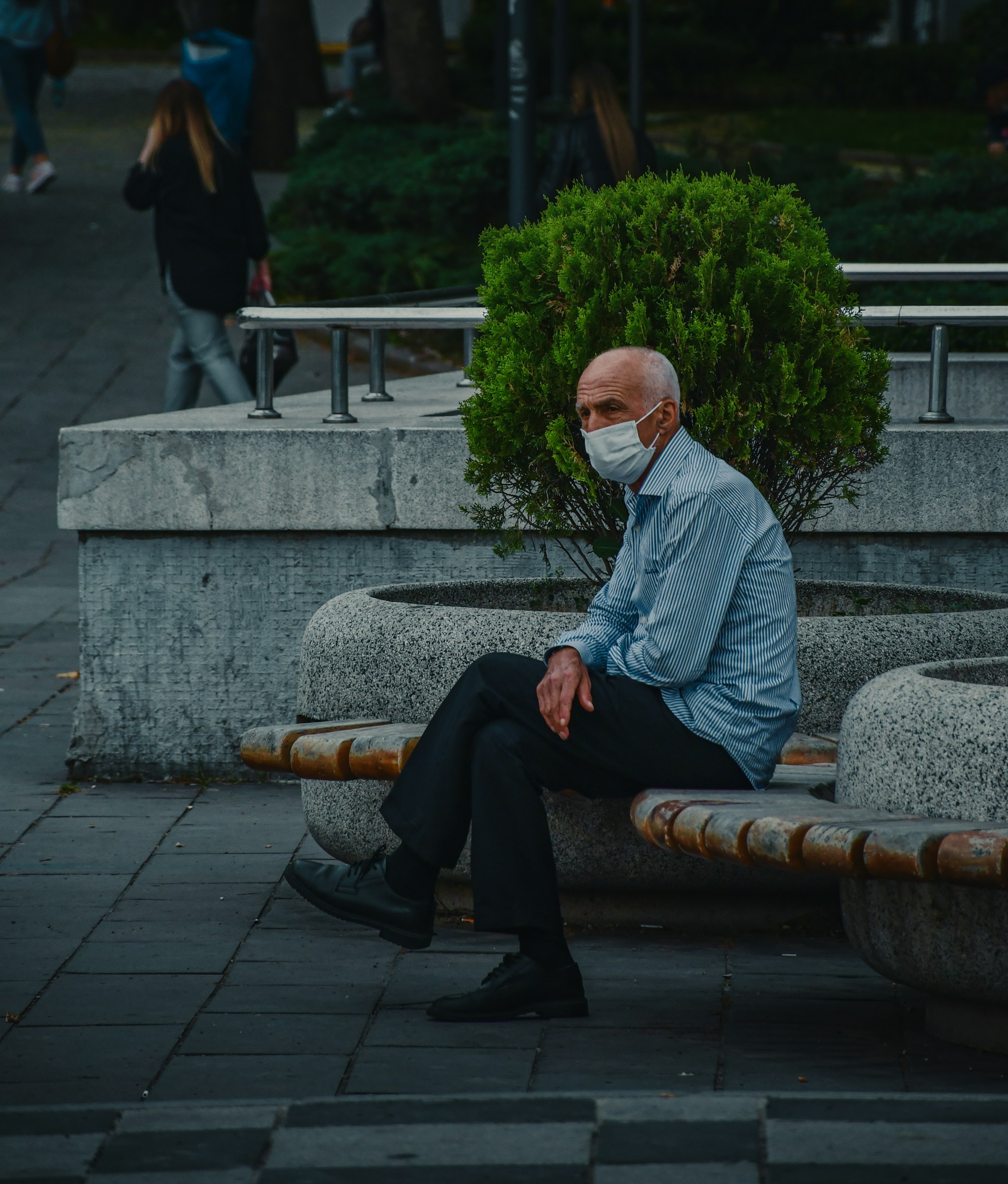 man in white dress shirt and black pants sitting on gray concrete bench