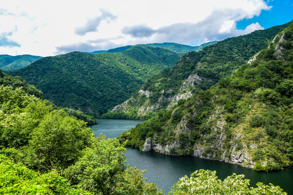 green mountains beside river under blue sky during daytime