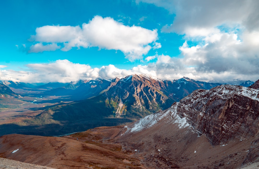 brown and white mountains under blue sky and white clouds during daytime