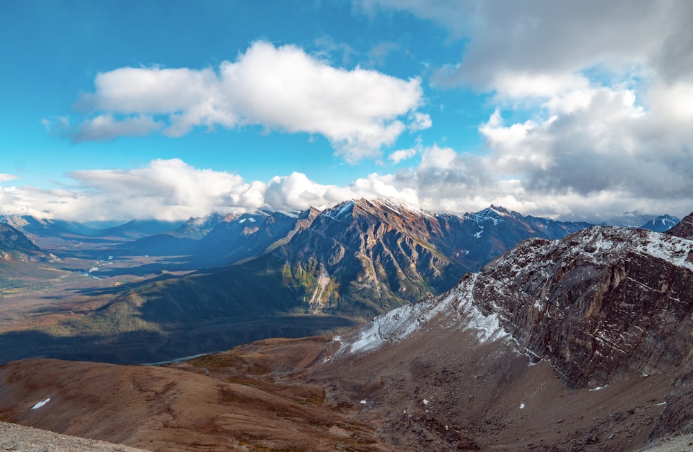 brown and white mountains under blue sky and white clouds during daytime