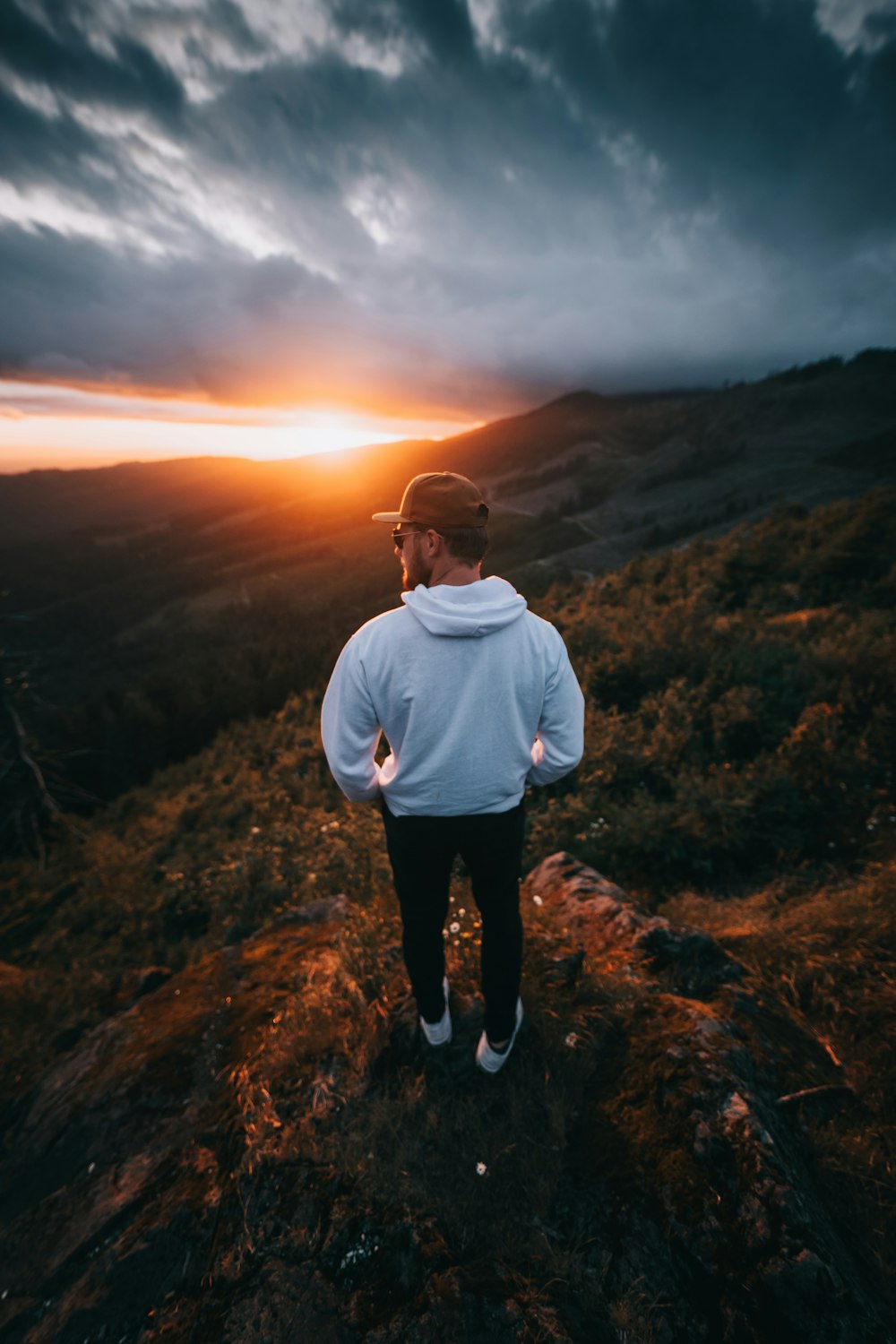 man in white sweater standing on brown grass field during sunset