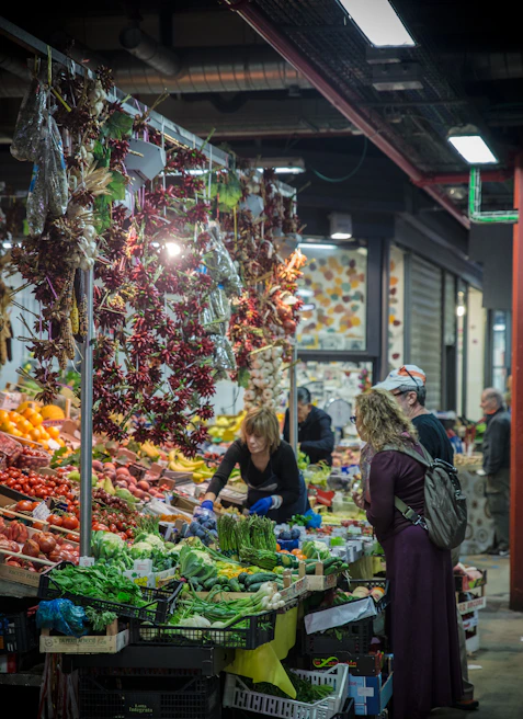 A bustling Spanish market stall filled with fresh fruits, vegetables, and lively conversations among neighbors.