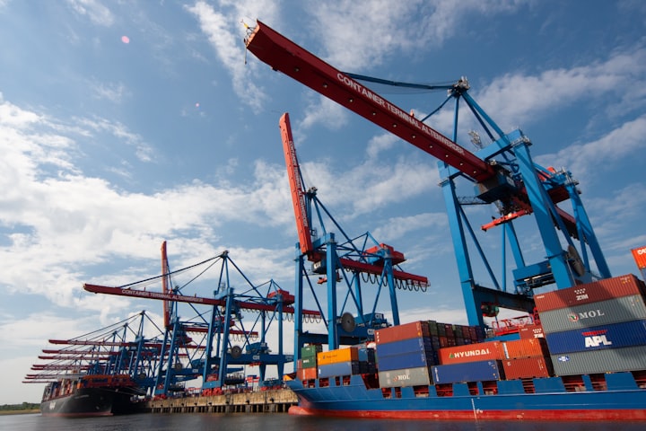 A picture of shipping boats with cargo containers in a harbor being loaded and unloaded