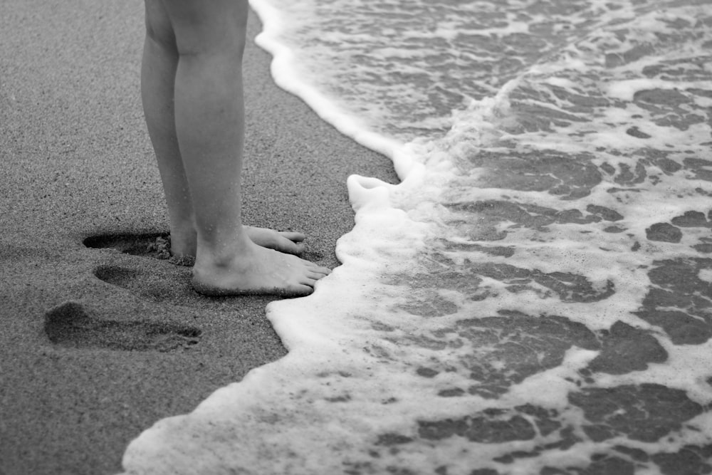 해변에서 산책하는 여자의 그레이스케일 사진