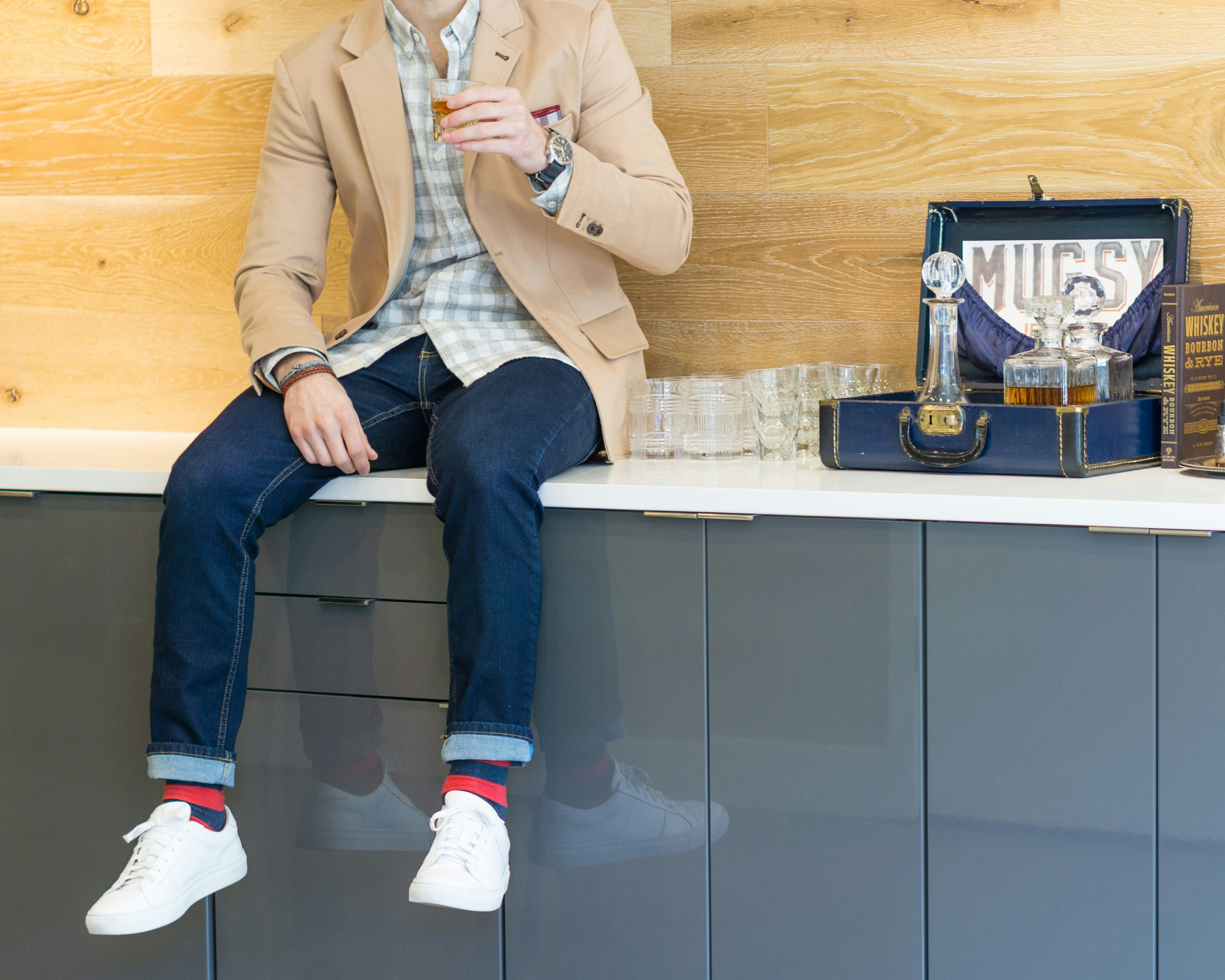 man in brown suit jacket and blue denim jeans sitting on white wooden table