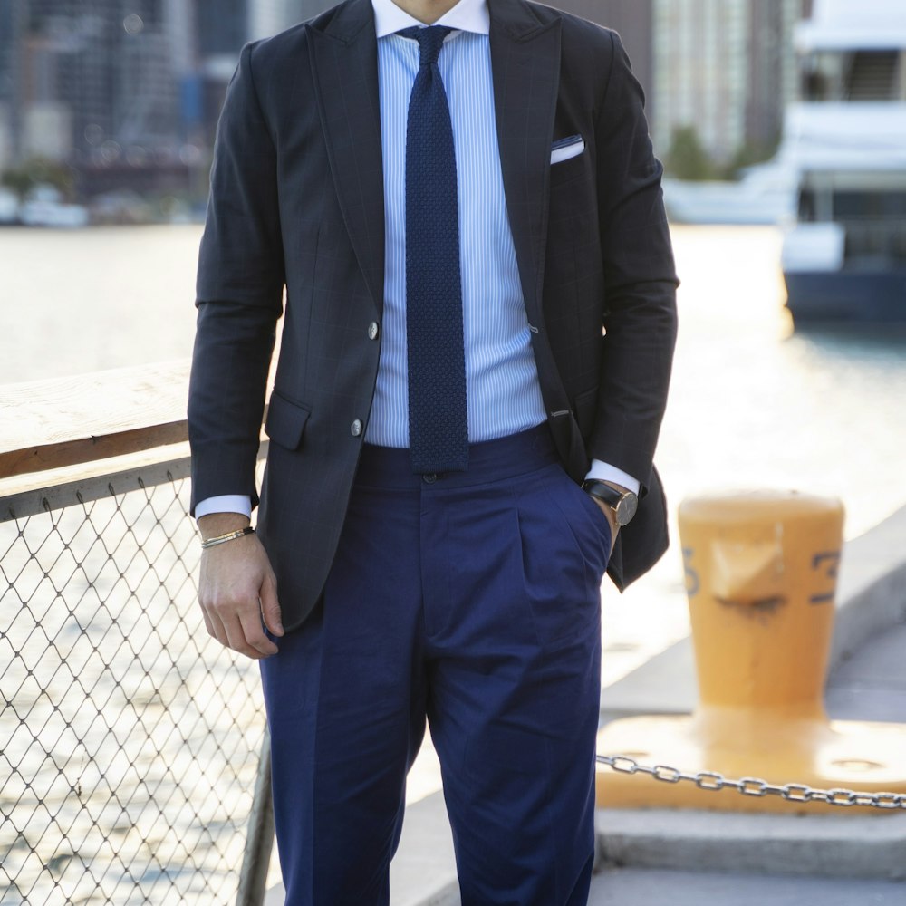 man in blue suit standing near gray metal fence during daytime