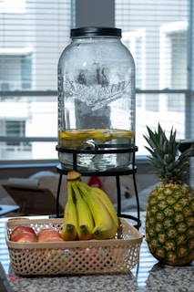 A clear glass filled with apple cider vinegar surrounded by fresh apples on a kitchen counter.