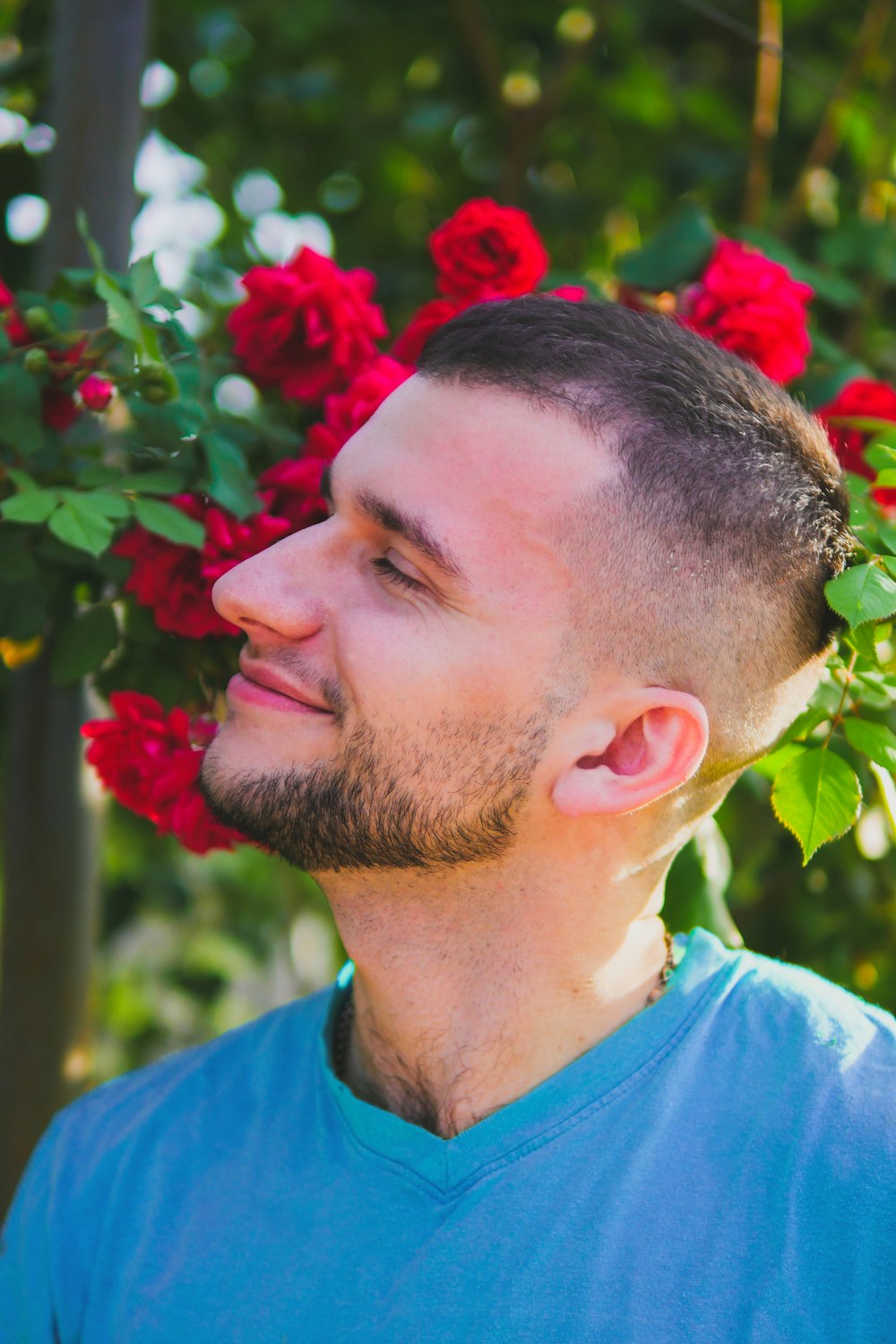 man in blue crew neck shirt with red flower on his ear