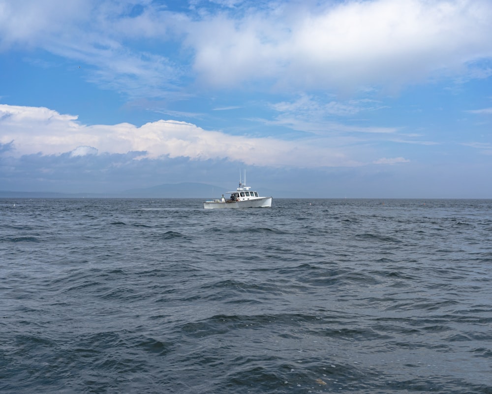 white boat on sea under blue sky and white clouds during daytime