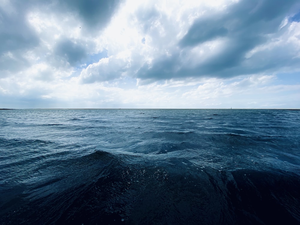 oceano sob nuvens brancas e céu azul durante o dia