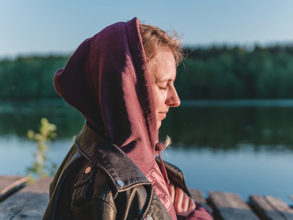 woman in red hoodie near body of water during daytime