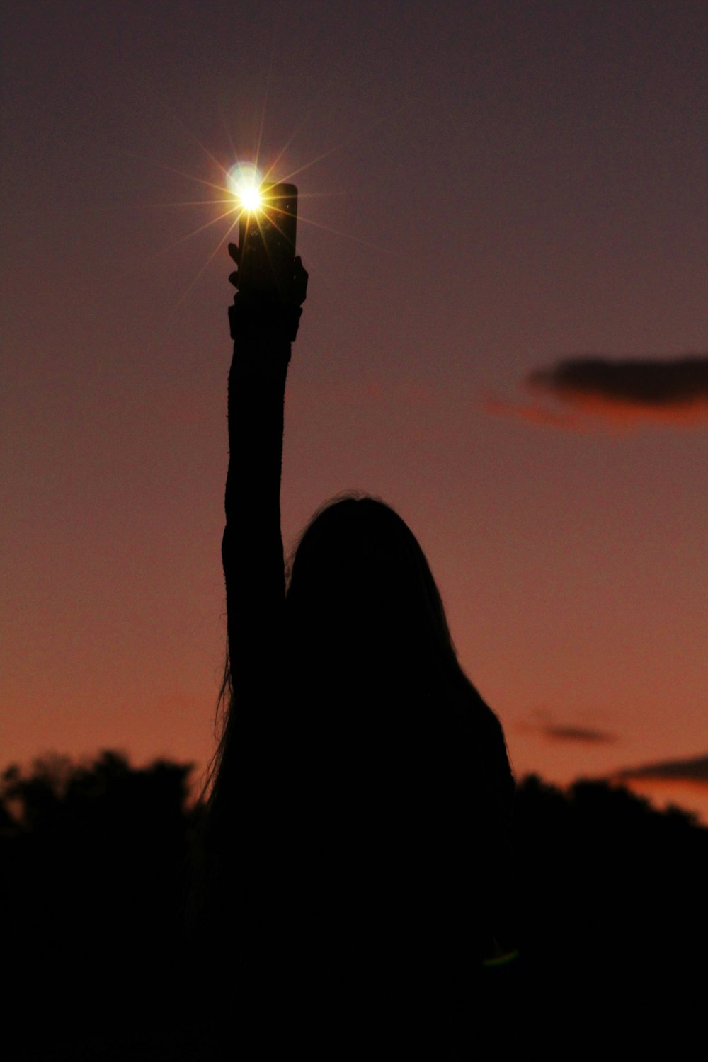 silhouette of woman holding sun