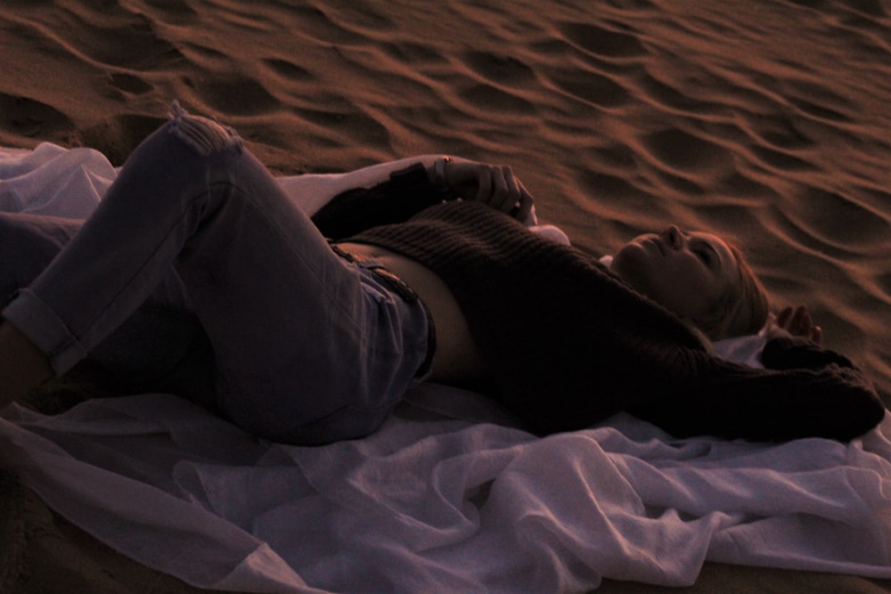 Frau im schwarzen Hemd auf braunem Sand liegend