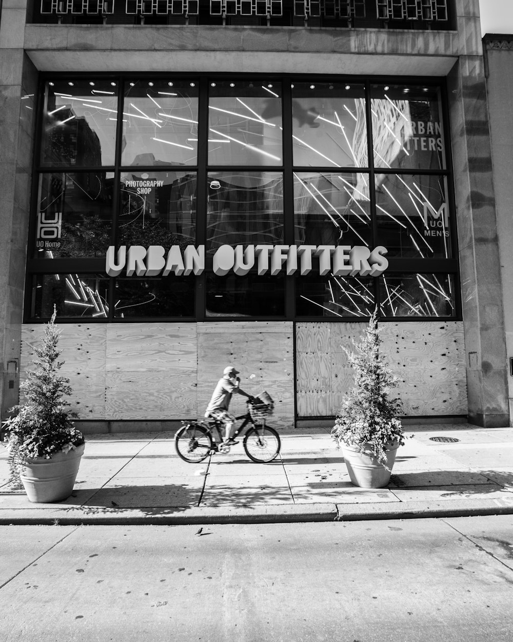 grayscale photo of girl riding bicycle in front of the UNKs coffee shop