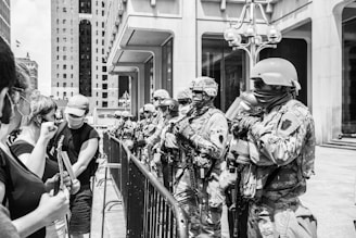 grayscale photo of 2 men in camouflage uniform standing near railings