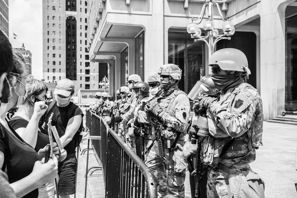 grayscale photo of 2 men in camouflage uniform standing near railings