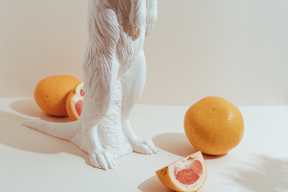 white angel figurine beside orange fruit