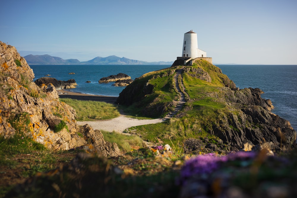 Phare blanc sur un champ d’herbe verte près d’un plan d’eau pendant la journée