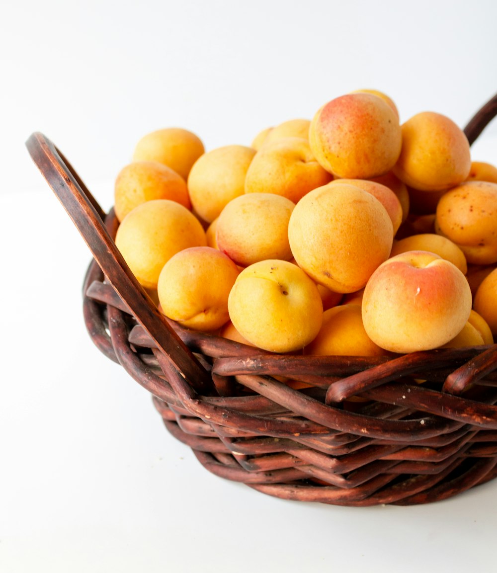 yellow round fruits on brown woven basket