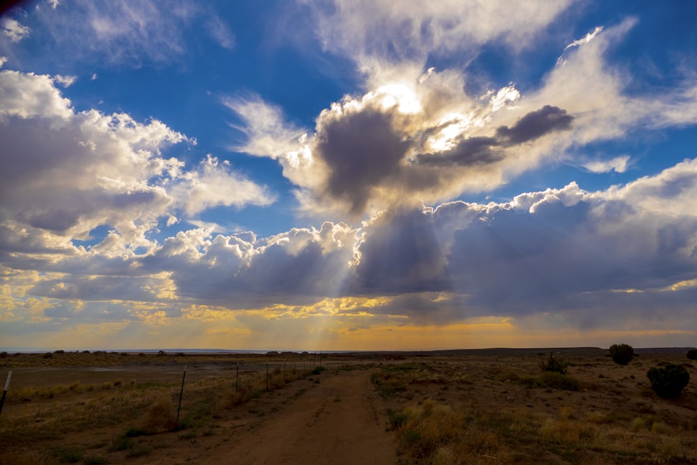 brown field under blue and white cloudy sky during daytime