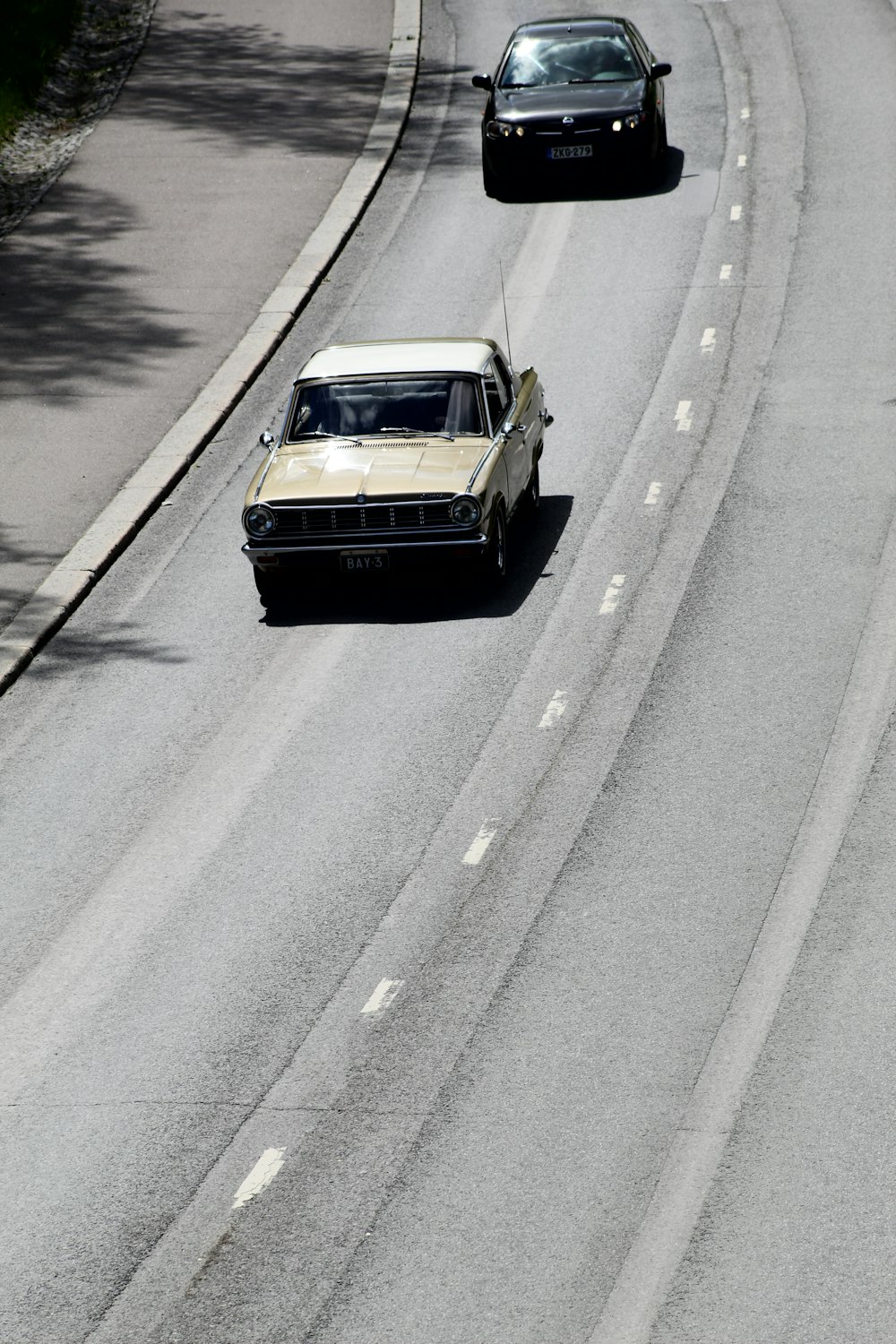 昼間の道路上の黒と白の車