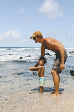 man in blue shorts and brown hat running on beach during daytime
