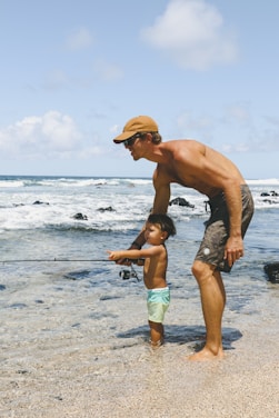 man in blue shorts and brown hat running on beach during daytime