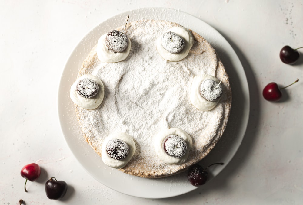 white and black round cake with black berries on white ceramic plate
