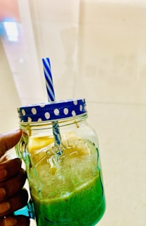 A refreshing green smoothie in a mason jar with a striped straw.