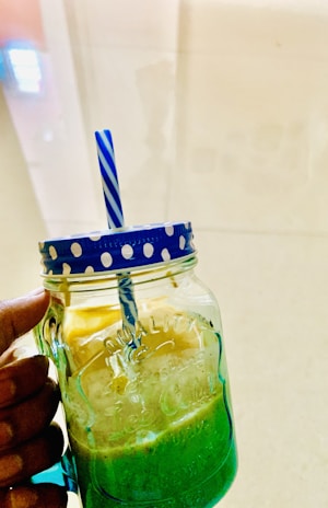 A refreshing green smoothie in a mason jar with a striped straw.