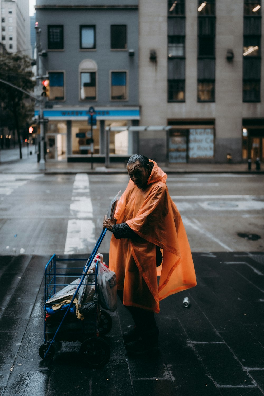 Mann in orangefarbener Robe sitzt tagsüber auf dem Bürgersteig