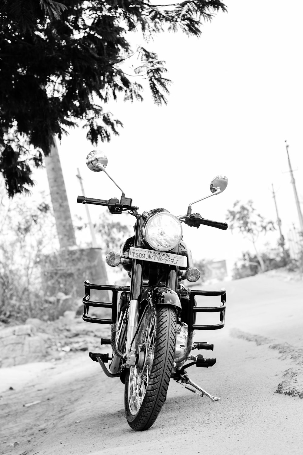 Foto en escala de grises de una motocicleta estacionada en la carretera
