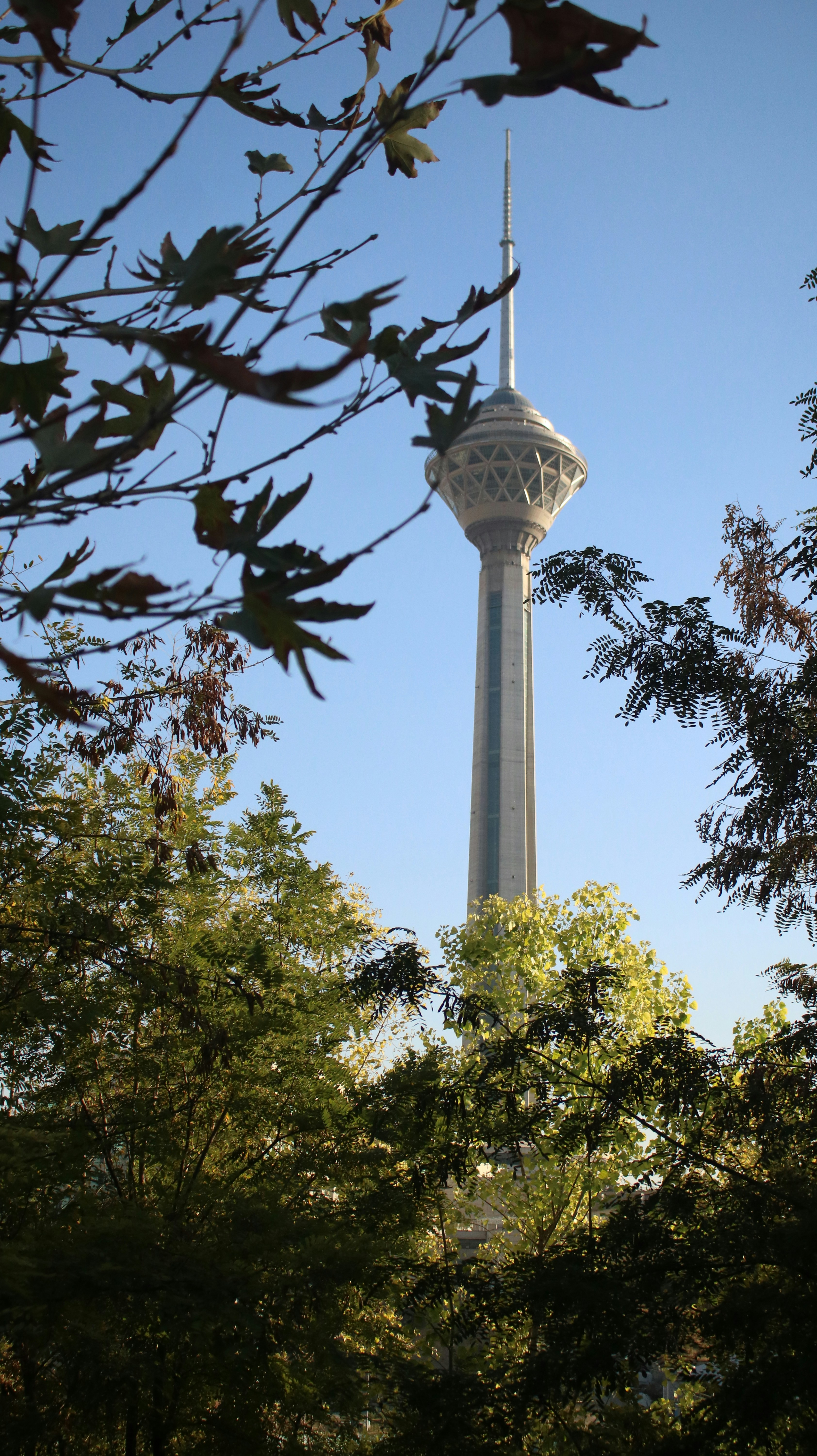white concrete tower near green trees during daytime