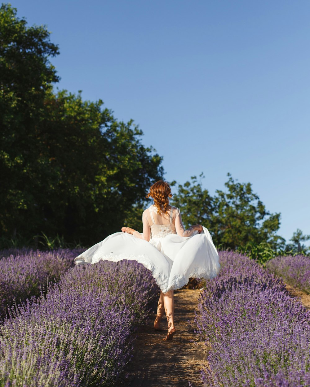 woman in white dress on purple flower field during daytime