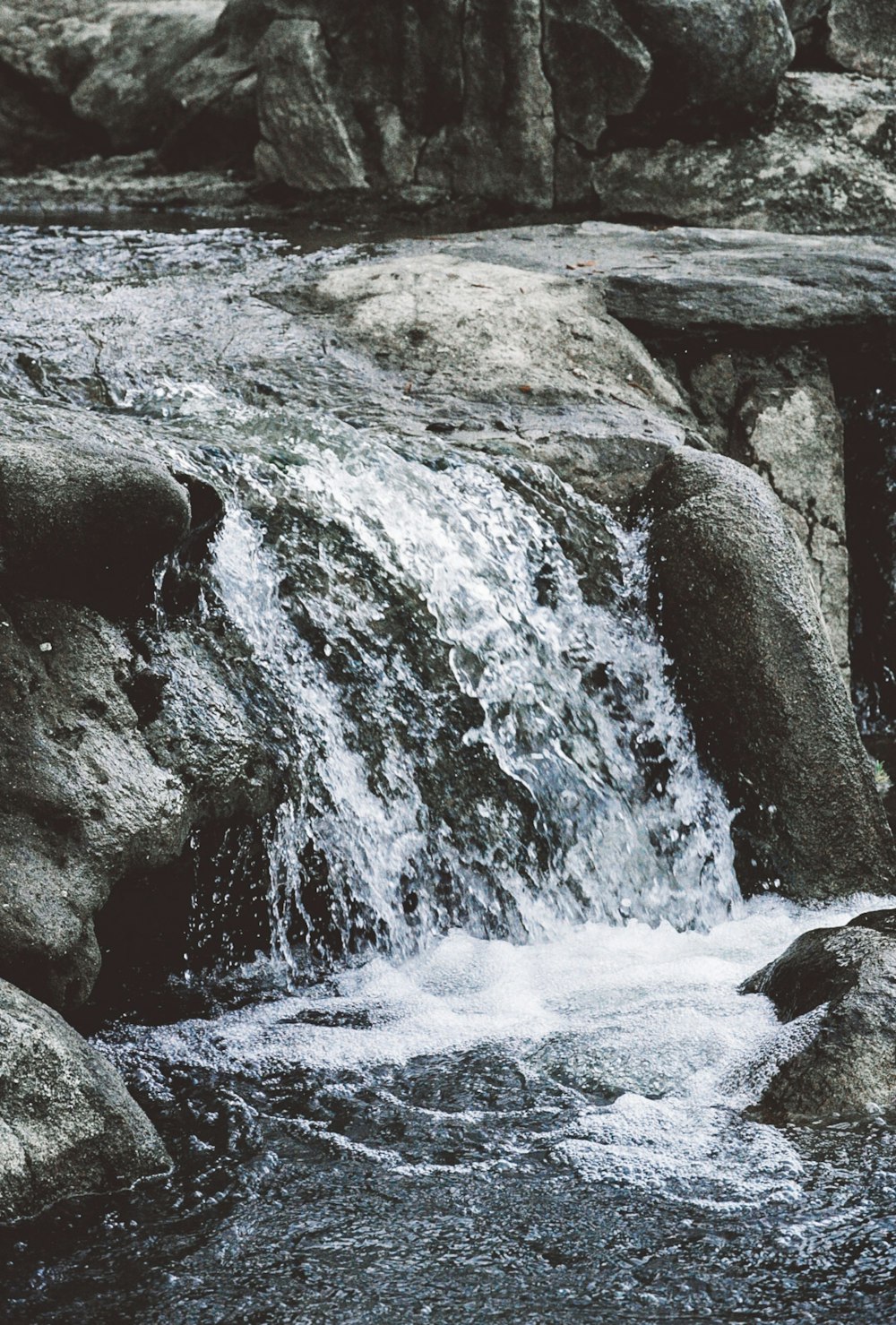 a man standing on a rock next to a waterfall