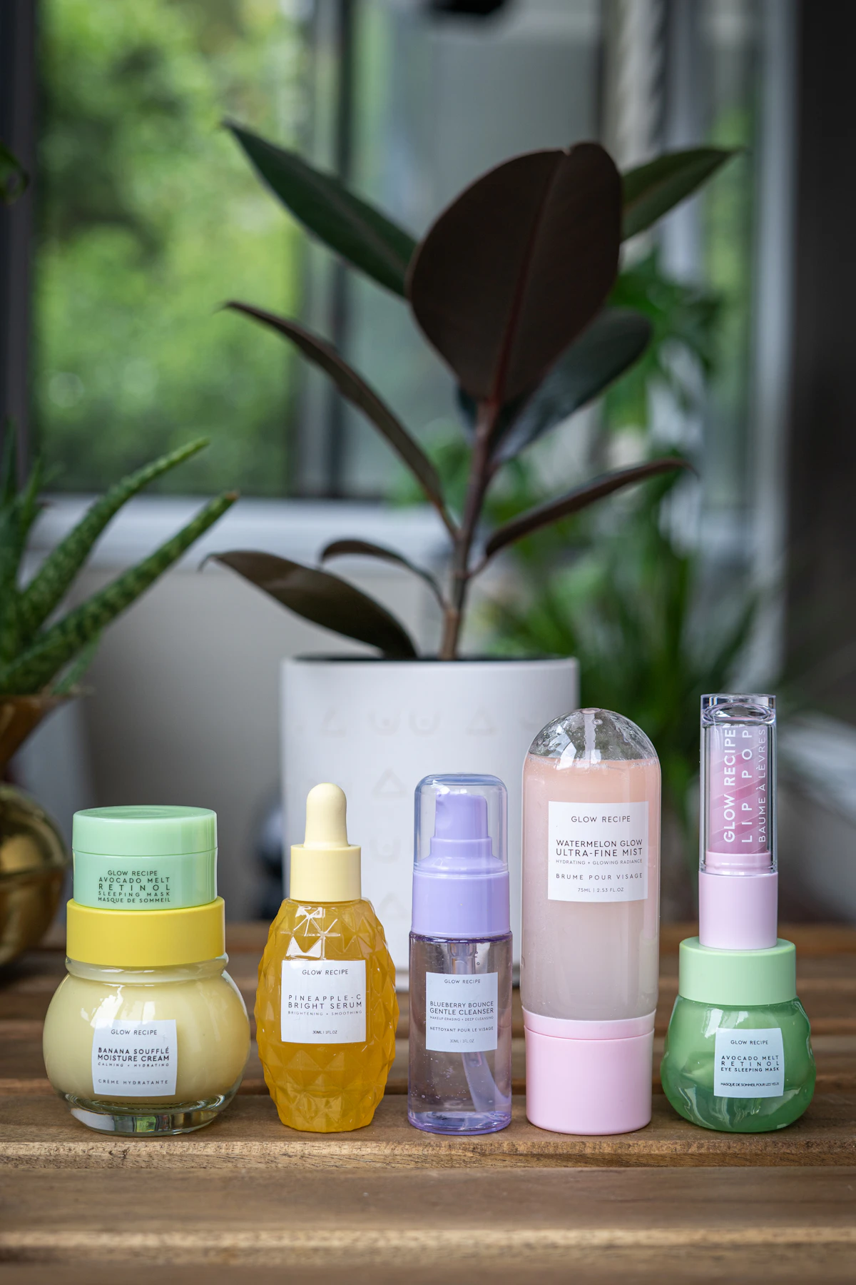 Yellow and pink skincare bottles arranged together on a soft pink background