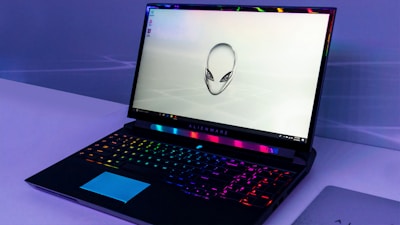 Sleek gaming laptop with vibrant RGB keyboard glowing in a dark room.