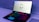 A sleek gaming laptop with a vibrant backlit keyboard and an iconic alien head logo displayed on the screen. The laptop sits on a minimalistic surface, and the lighting around the device creates a futuristic ambiance.